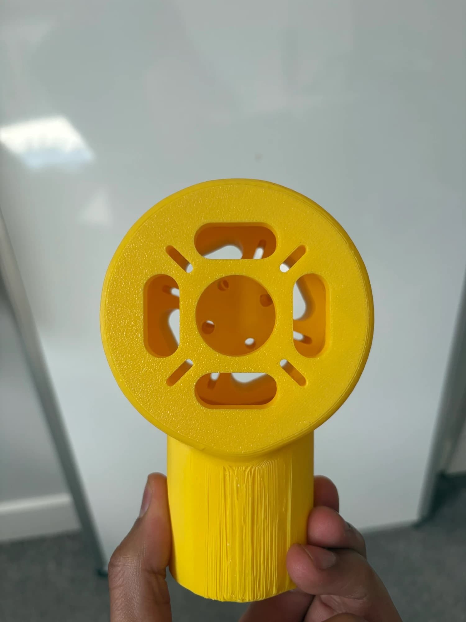 top-down view of the yellow motor mount face showing the motor boss recess, screw holes and cutouts